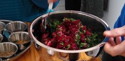 Eine Metallschüssel, in der sich Rote Beete Salat befindet, der gerade vermengt wird.